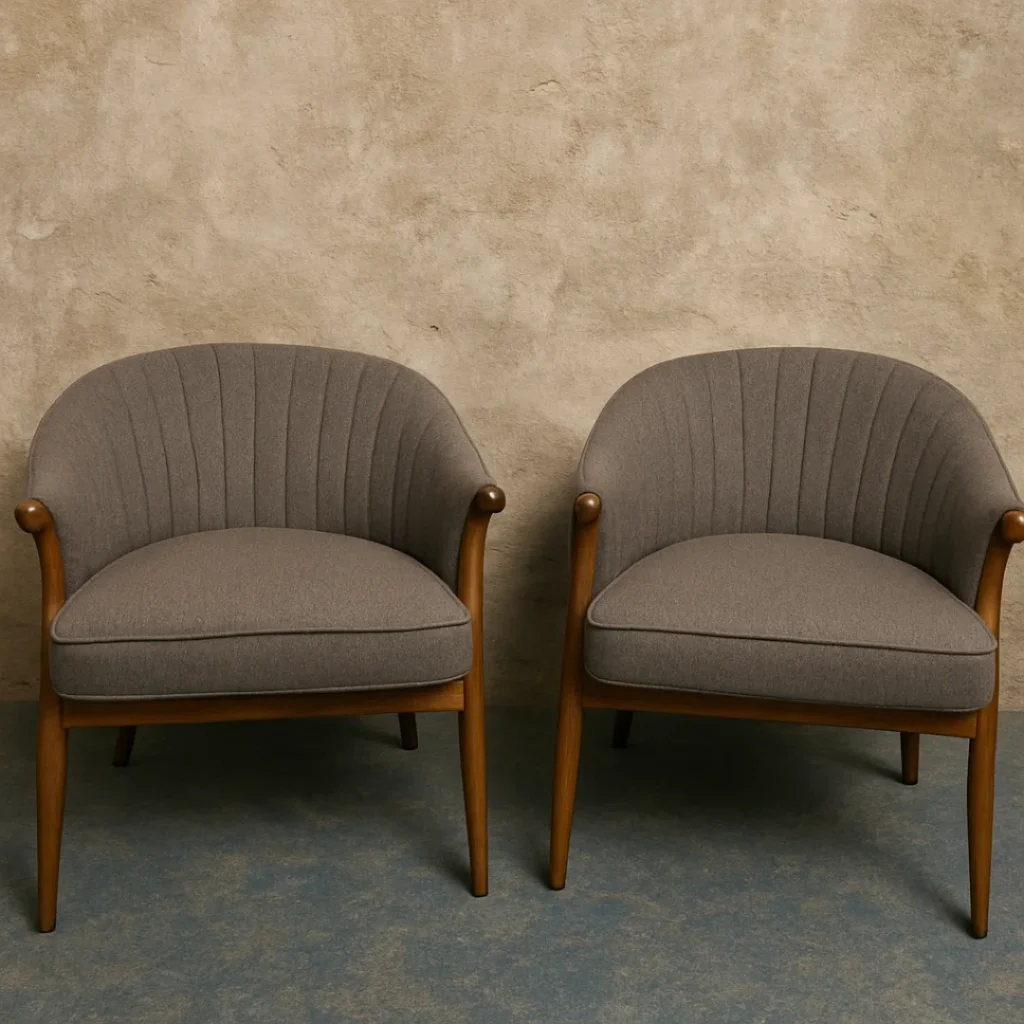 Matching pair of grey wool tub chairs with oak frames against plaster wall
