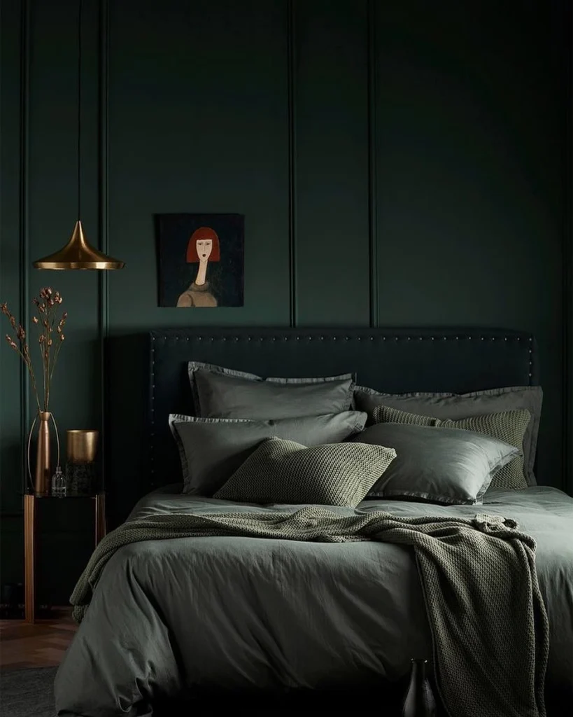 Moody dark forest green paneled bedroom with brass pendant light