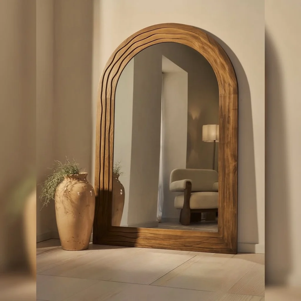 Layered arch dark walnut wood frame floor mirror beside ceramic vase with greenery