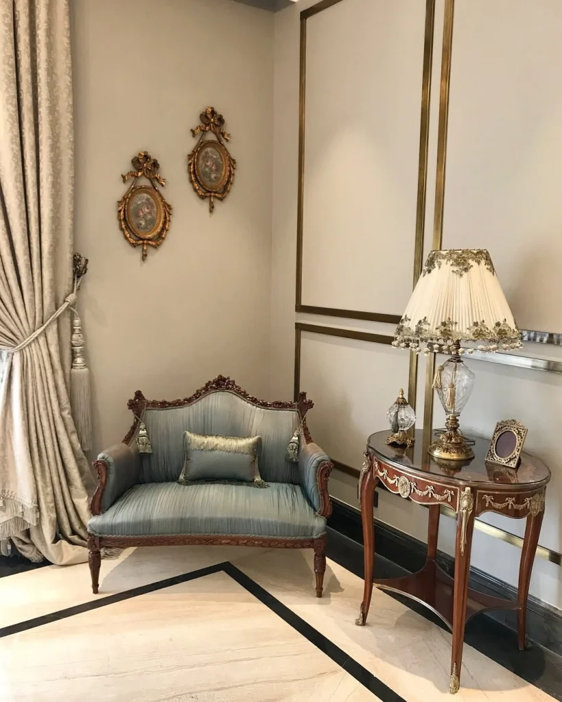 French-style teal settee with gold ornate frames, crystal lamp, and marble side table
