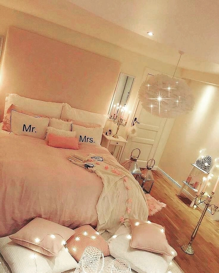 Warm personal couple's bedroom with blush pink walls, white feather pendant shade